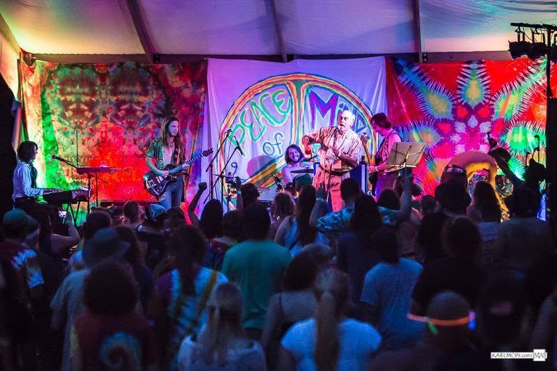 A packed crowd in front of a Peace of Mind tie-dye stage banner